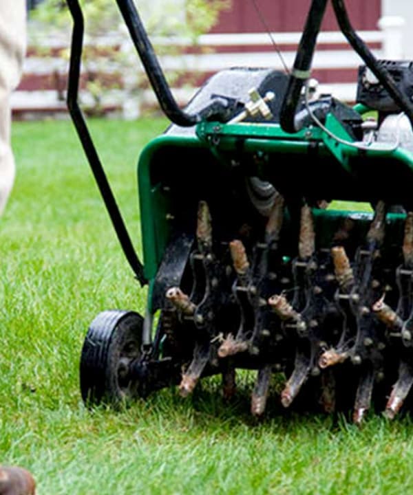 A person aerating a lawn as autumn approaches